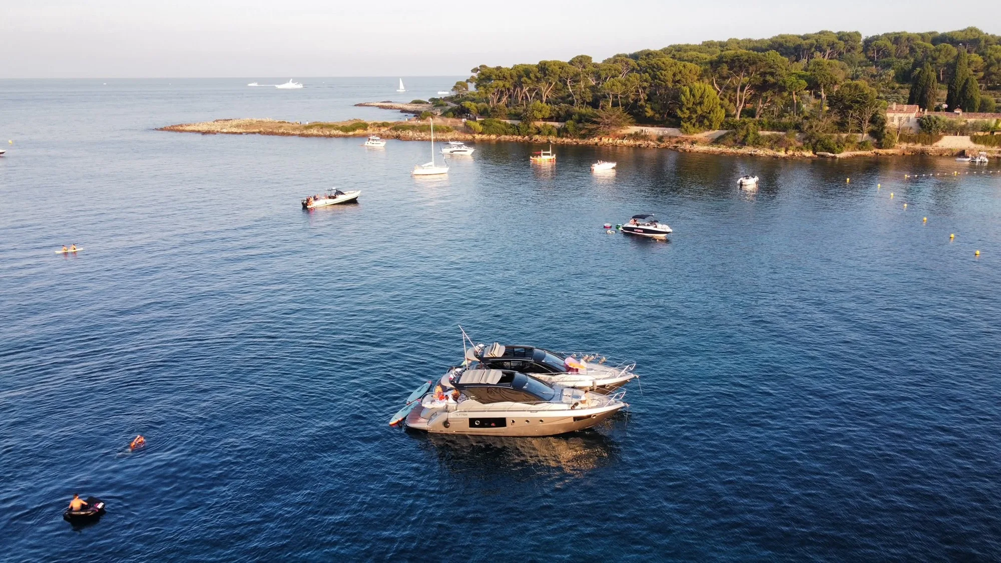 Deux bateaux de la flotte à couple au mouillage au large des Lérins, les invités se baignant autour.