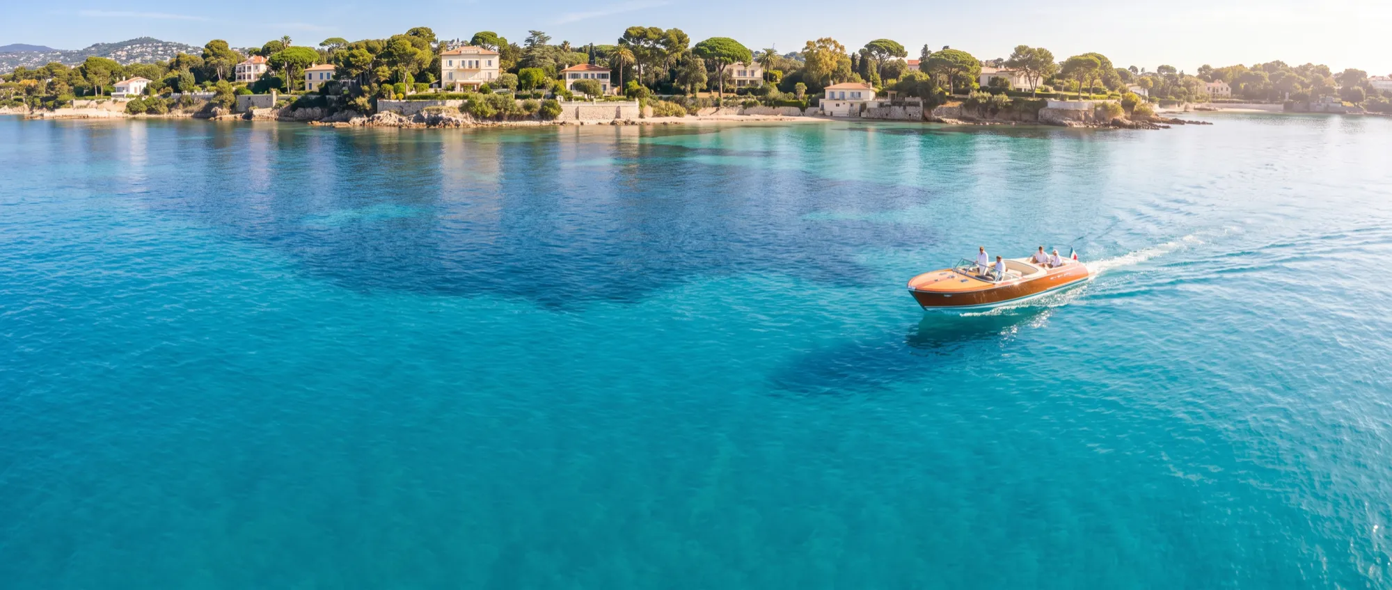 Un bateau à la journée, seul sur l'eau turquoise au large du Cap Ferrat, en plein milieu de journée.