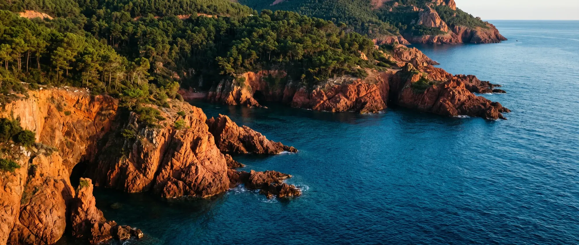 The red porphyry cliffs of the Estérel falling into clear blue water.