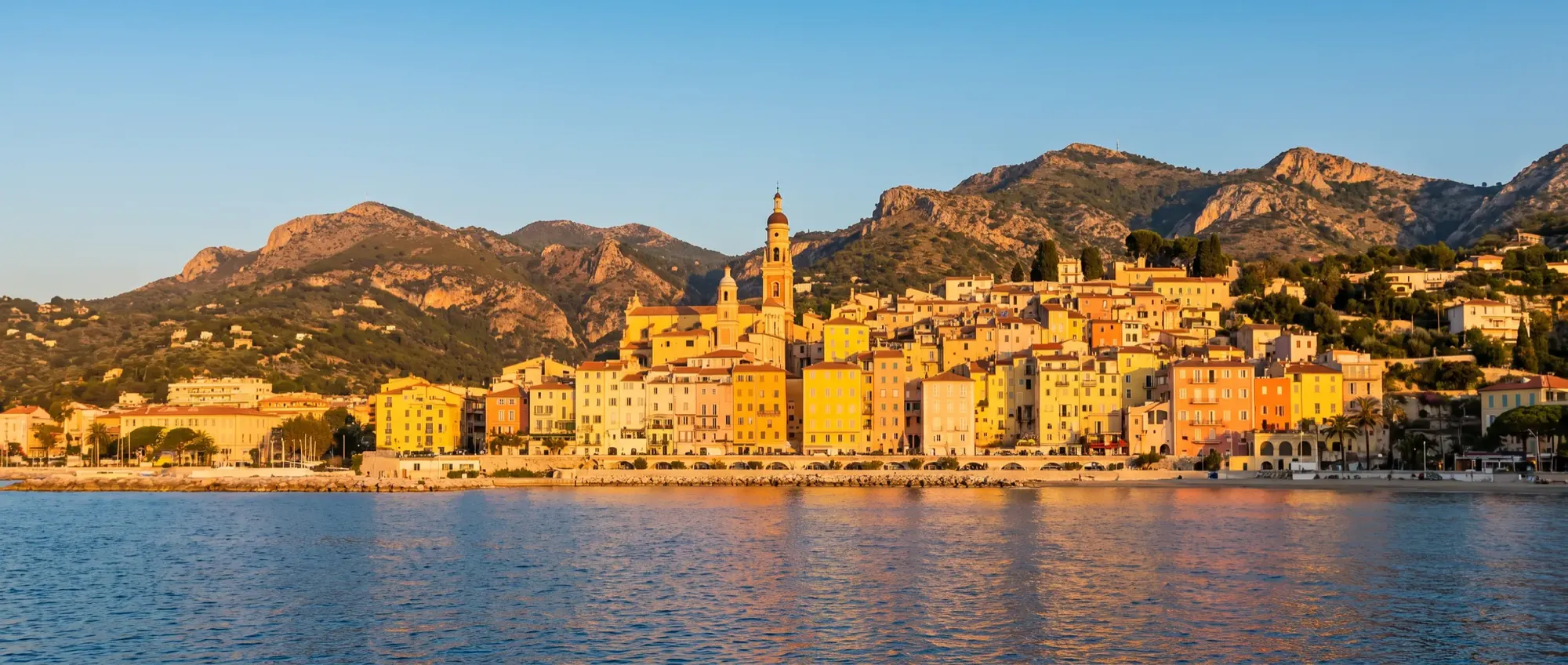 The lemon and apricot façades of Menton old town seen from the sea.