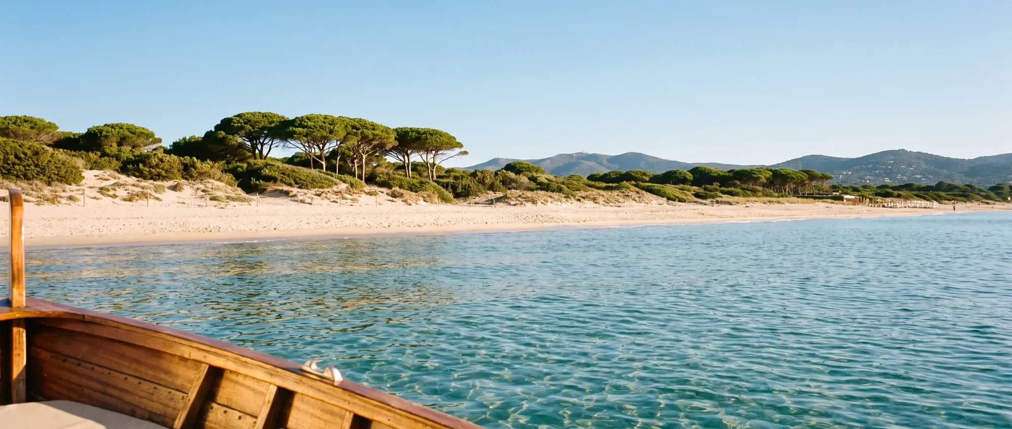 The long pale sand of Pampelonne seen from the water with turquoise shallows.