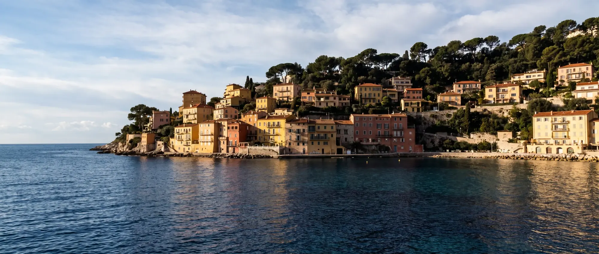The deep bay of Villefranche-sur-Mer seen from the water, pastel houses rising up the hillside.