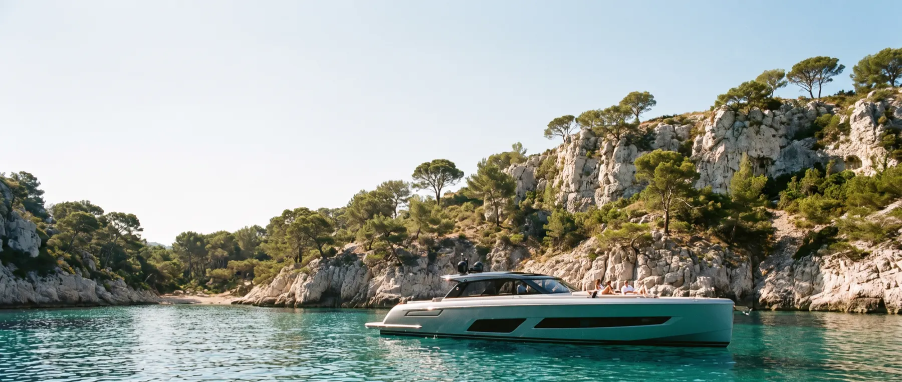 A day boat anchored alone in a turquoise cove.