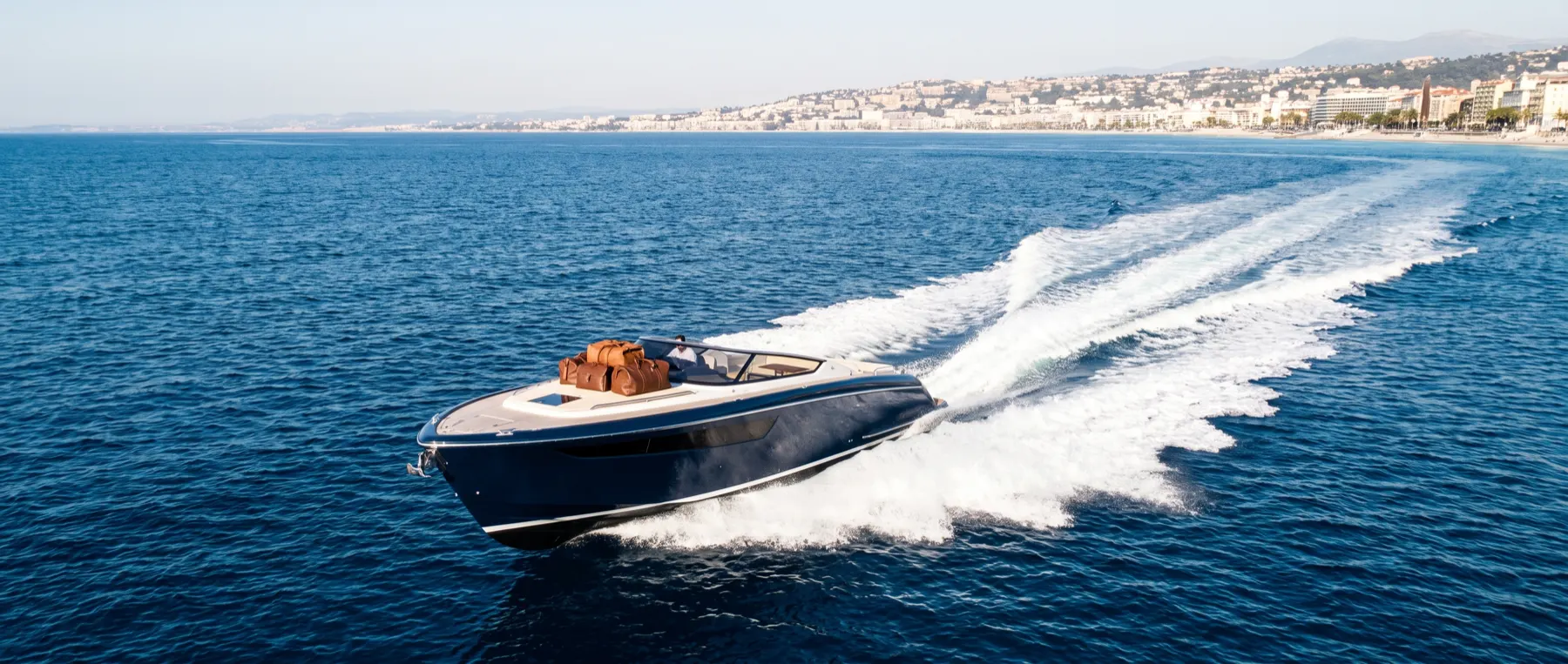A day yacht underway along the coast, carrying guests to their destination.