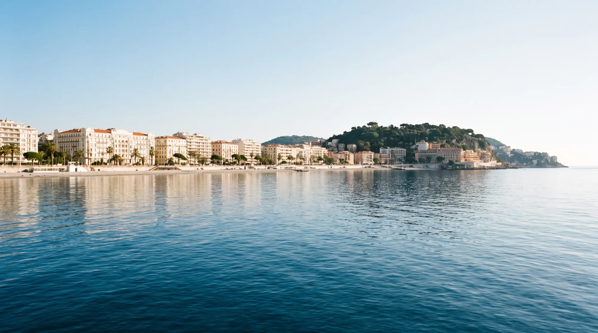 La baie de Nice depuis l’eau, la Promenade s’incurvant sous la colline du Château.